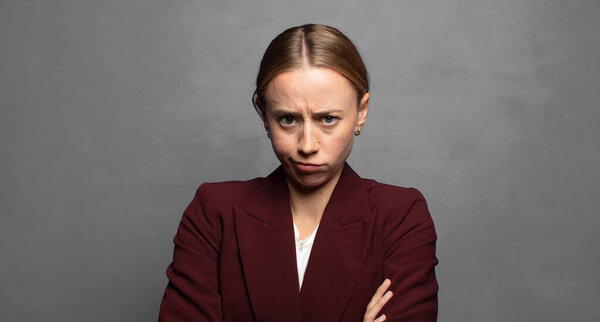 недовольна и разочарована, выглядит серьезной, раздраженной и злой со скрещенными руками