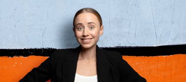 Mutlu bir şekilde gülümsüyor, elleri kalçasında ve kendinden emin, gururlu ve arkadaş canlısı bir tavırla