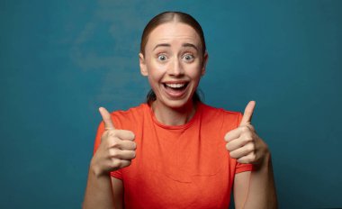 Neşeli bir şekilde gülümsüyor ve mutlu görünüyor, tasasız ve pozitif hissediyor.