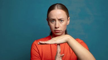 Ciddi görünüyor, sert, kızgın ve hoşnutsuz, mola işareti yapıyor.