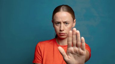 Ciddi, sert, hoşnutsuz ve kızgın görünüyor. Avuç içini açıp, jestleri durduruyor.