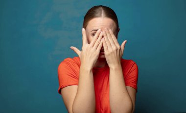 Yüzü ellerle kaplamak, parmaklarının arasından bakmak şaşırmış bir ifadeyle yan tarafa bakmak.