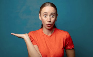 Şaşırmış ve şoke olmuş bir halde, çenesi düşmüş bir objeyi elinde açık bir elle tutarken.