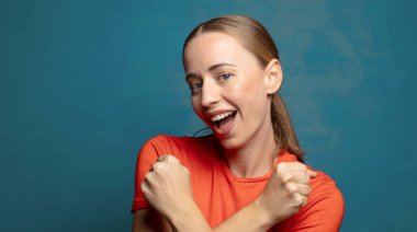 Neşeli bir şekilde gülümseyen ve kutlayan, yumruklarını sıkan, kollarını kavuşturan, mutlu ve pozitif hisseden