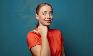 Neşeli bir şekilde gülümsüyor ve yan taraftaki fotokopi alanını işaret ediyor, mutlu ve tatmin olmuş hissediyordu.