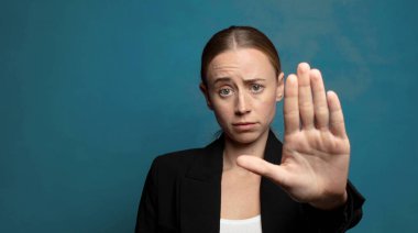 Ciddi, sert, hoşnutsuz ve kızgın görünüyor. Avuç içini açıp, jestleri durduruyor.