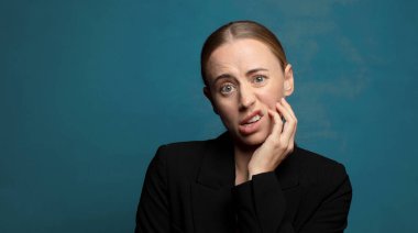 Şok ve inançsızlıkla ağzı açık, elleri yanakları ve kolları çaprazlanmış, sersemlemiş ve şaşkın.