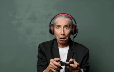 Gayri resmi kıyafetli, elinde oyun sahası ve video oyun kumandası olan siyah arka planda sürpriz bir adam.