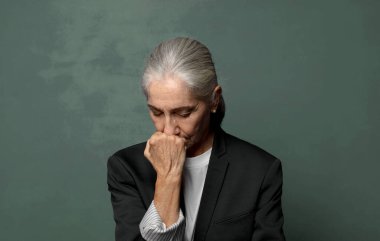  Ciddi, düşünceli ve endişeli hissediyorum. Elleri çenesine değmiş şekilde yan yan bakıyor.