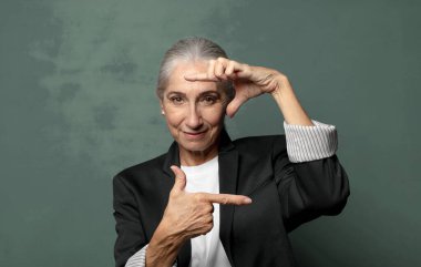  Mutlu, arkadaş canlısı ve pozitif hissediyorum, gülümsüyor ve elleriyle bir portre veya fotoğraf çerçevesi yapıyor.