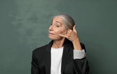  Neşeli bir şekilde gülümsüyor ve telefonla konuşurken kamerayı işaret ediyor.