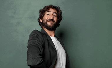  Mutlu bir şekilde gülümsüyor, eli kalçasında ve kendinden emin, olumlu, gururlu ve arkadaş canlısı bir tavırla.