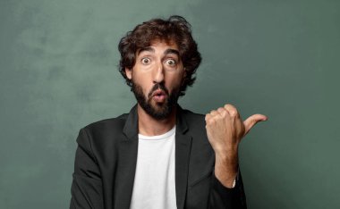  İnançsızlıktan şaşkın şaşkın bakıyor, yan taraftaki objeyi işaret ediyor ve 