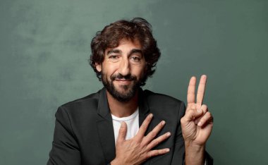  Mutlu, kendinden emin ve güvenilir görünüyor, gülümsüyor ve olumlu bir tavırla zafer işareti gösteriyor.