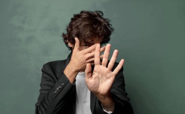  Yüzünü eliyle kapatıyor ve kamerayı durdurmak için diğer elini öne koyuyor, fotoğraf ya da resimleri reddediyor.