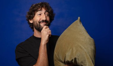 Genç sakallı çılgın adam yastığa sarılıyor.