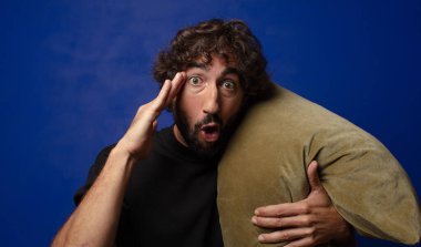 Genç sakallı çılgın adam yastığa sarılıyor.