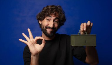 Genç sakallı çılgın adam elinde bir tasarruf kutusu tutuyor.