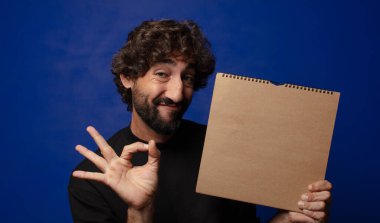 Boş defter kapağı olan genç sakallı deli adam.