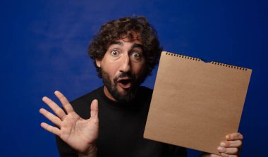 Boş defter kapağı olan genç sakallı deli adam.