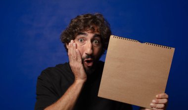 Boş defter kapağı olan genç sakallı deli adam.