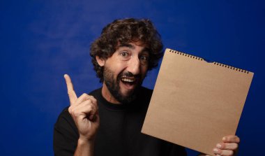 Boş defter kapağı olan genç sakallı deli adam.