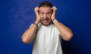 Şaşırmış, kafası karışmış ve stresli görünüyor, farklı seçenekler arasında merak ediyor, kararsız hissediyor.