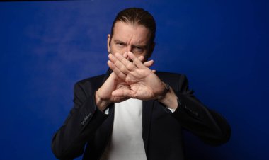 Yüzünü eliyle kapatıyor ve kamerayı durdurmak için diğer elini öne koyuyor, fotoğraf ya da resimleri reddediyor.