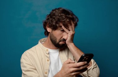 Akıllı telefonu olan genç, sakallı bir adam.