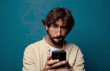 Akıllı telefonu olan genç, sakallı bir adam.