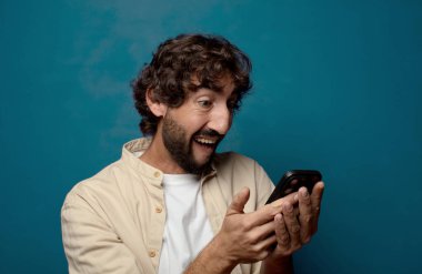 Akıllı telefonu olan genç, sakallı bir adam.