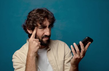 Akıllı telefonu olan genç, sakallı bir adam.