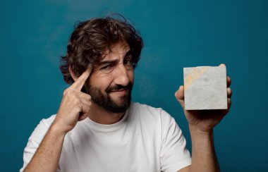 Taştan bir tuğlası olan sakallı genç bir adam.