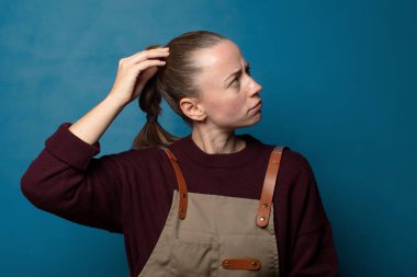 Kadın şaşkın ve şaşkın hissediyor, başını kaşıyor ve yan tarafa bakıyor.