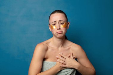 Üzgün, yaralı ve kalbi kırık görünüyor, iki elini de kalbe yakın tutuyor, ağlıyor ve depresif hissediyor.