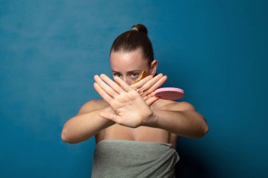 Yüzünü eliyle kapatıyor ve kamerayı durdurmak için diğer elini öne koyuyor, fotoğraf ya da resimleri reddediyor.