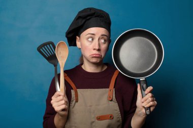 Sarışın, genç, güzel aşçı kadın yemek aletleriyle