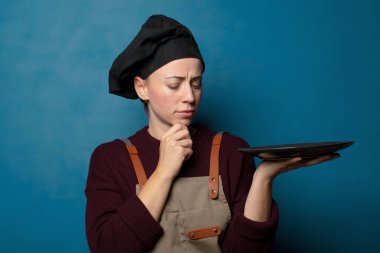 Sarışın, genç, güzel aşçı kadın. Boş tabağı var.