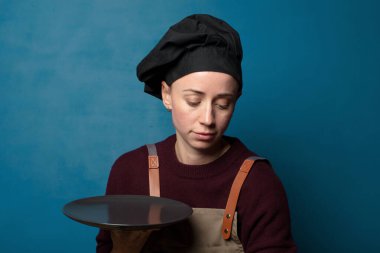 Sarışın, genç, güzel aşçı kadın. Boş tabağı var.