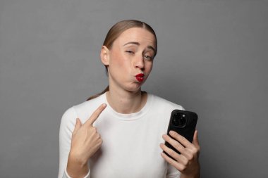 Kibirli ve agresif görünen, yukarıyı gösteren ya da ellerinle alay eden bir tavır takınarak.