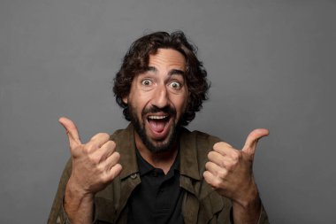 Neşeli bir şekilde gülümsüyor ve mutlu görünüyor, tasasız ve pozitif hissediyor.