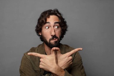 Şaşırmış ve kafası karışmış görünüyor, güvensiz ve şüpheyle zıt yönleri işaret ediyor.