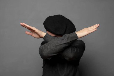 Yüzünü eliyle kapatıyor ve kamerayı durdurmak için diğer elini öne koyuyor, fotoğraf ya da resimleri reddediyor.