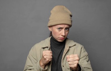 Kendinden emin, sinirli, güçlü ve agresif görünüyor. Yumrukları boks pozisyonunda dövüşmeye hazır.