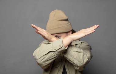 Yüzünü eliyle kapatıyor ve kamerayı durdurmak için diğer elini öne koyuyor, fotoğraf ya da resimleri reddediyor.