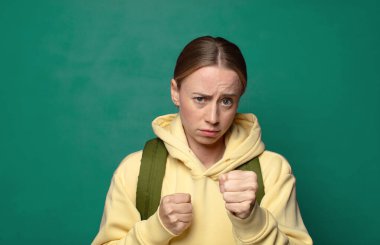 Kendinden emin, sinirli, güçlü ve agresif görünüyor. Yumrukları boks pozisyonunda dövüşmeye hazır.