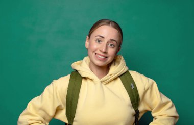 Mutlu bir şekilde gülümsüyor, elleri kalçasında ve kendinden emin, gururlu ve arkadaş canlısı bir tavırla