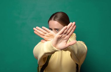 Yüzünü eliyle kapatıyor ve kamerayı durdurmak için diğer elini öne koyuyor, fotoğraf ya da resimleri reddediyor.