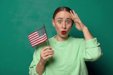 Yeşil stüdyo geçmişinde ABD bayrağı olan genç sarışın kadın.