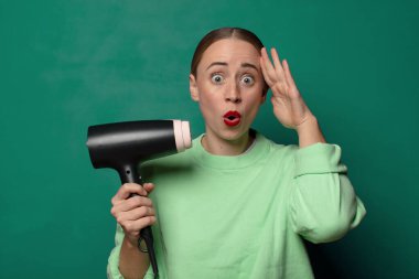 Saç kurutma makinesi olan genç sarışın kadın.